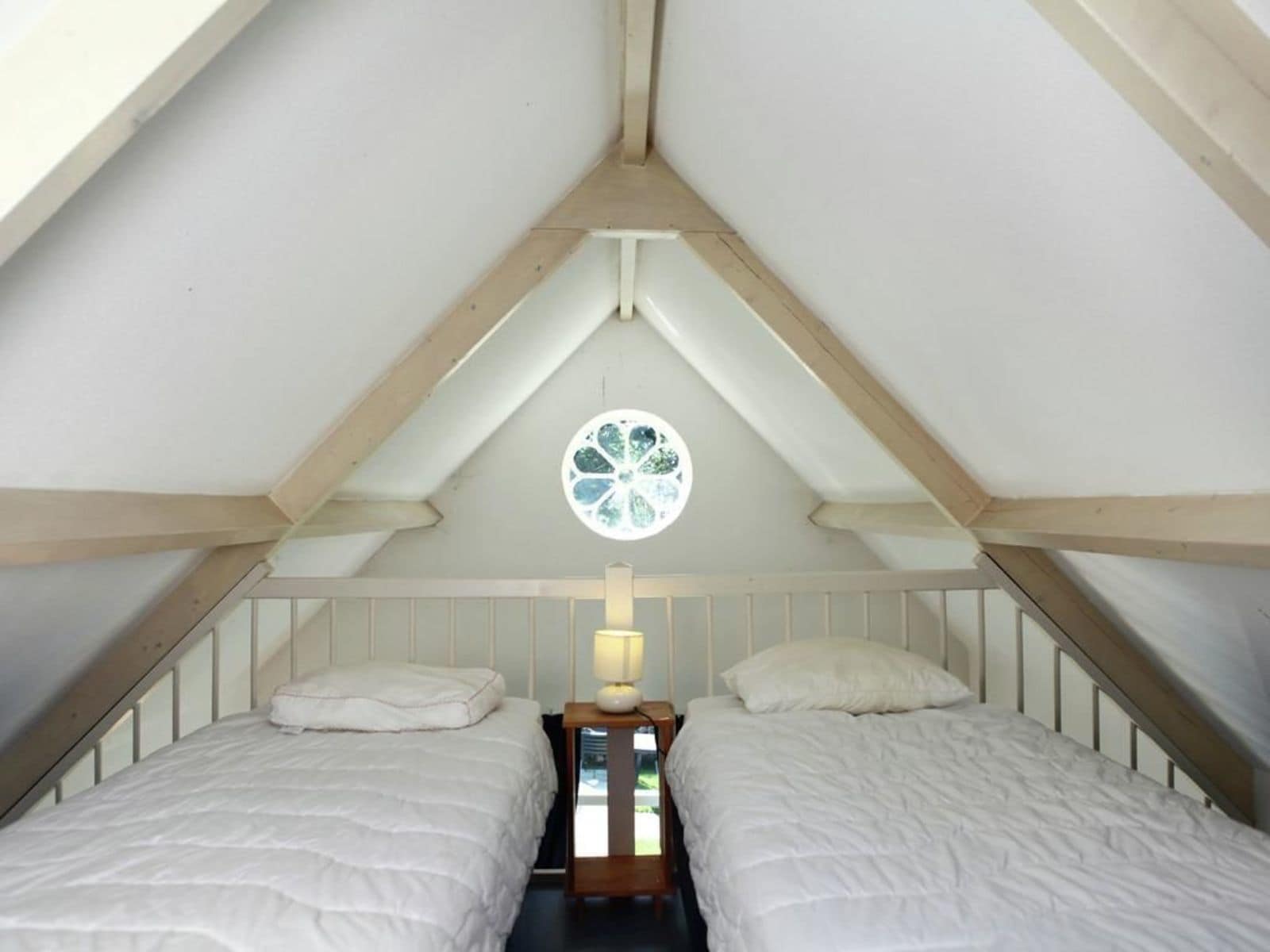 Un dormitorio con dos camas, una ventana con diseño floral y vigas de madera en el techo.