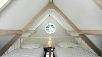 Un dormitorio con dos camas, una ventana con diseño floral y vigas de madera en el techo.