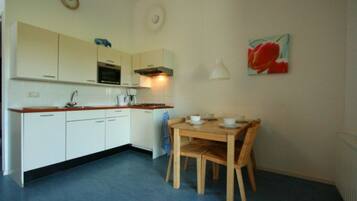 A compact kitchen with white cabinets, a wooden dining table, and a blue floor.