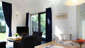 A dining area with a table set for two, a television, and a view of the outdoors. - Rijnhoeve (Koudekerk aan den Rijn)