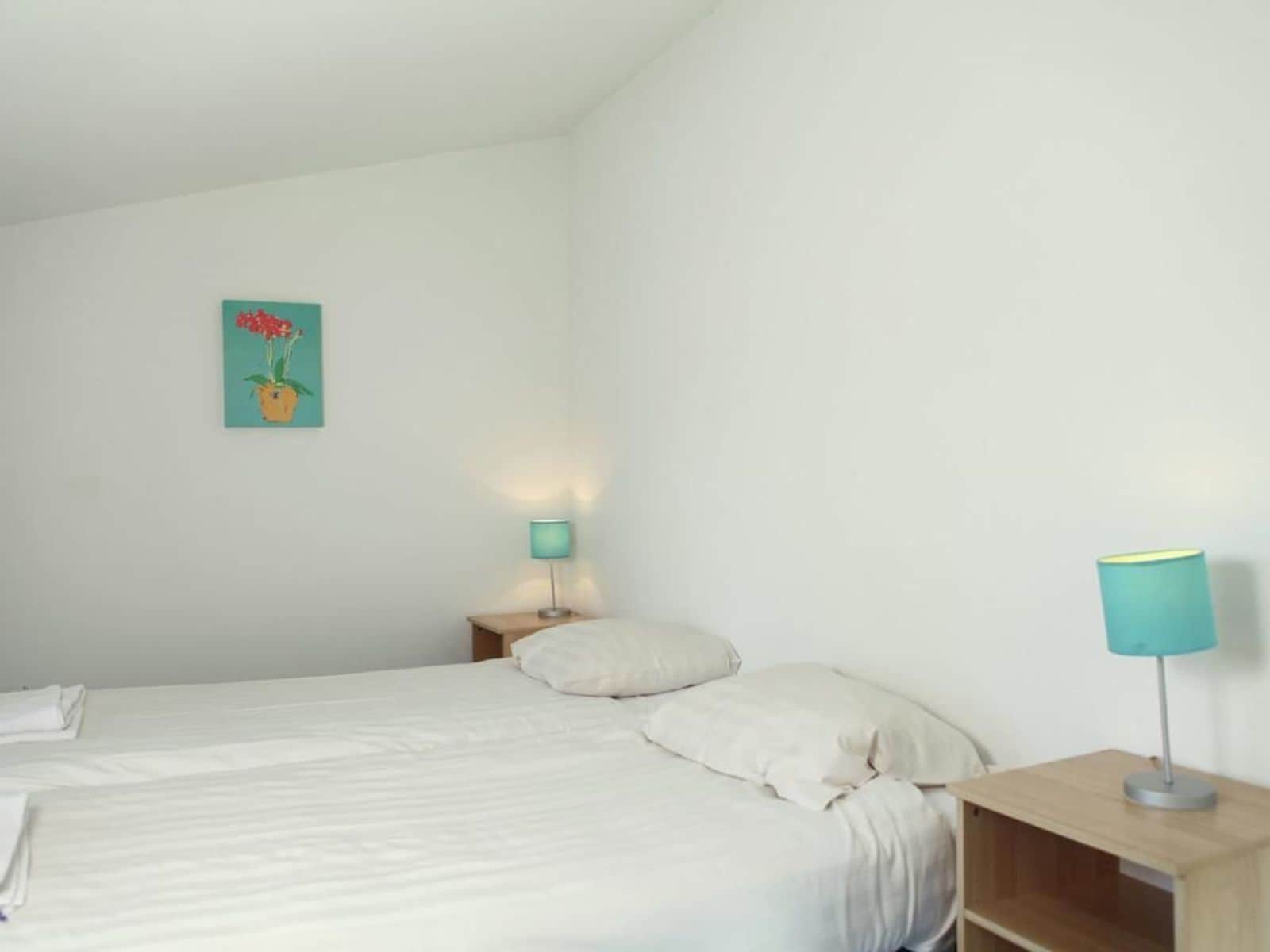Un dormitorio con cama, dos mesitas de noche y una lámpara de pared.