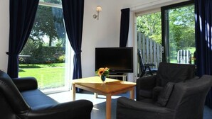 A living room with a flat-screen TV, two black sofas, a wooden coffee table, and a vase with flowers. - Rijnhoeve (Koudekerk aan den Rijn)