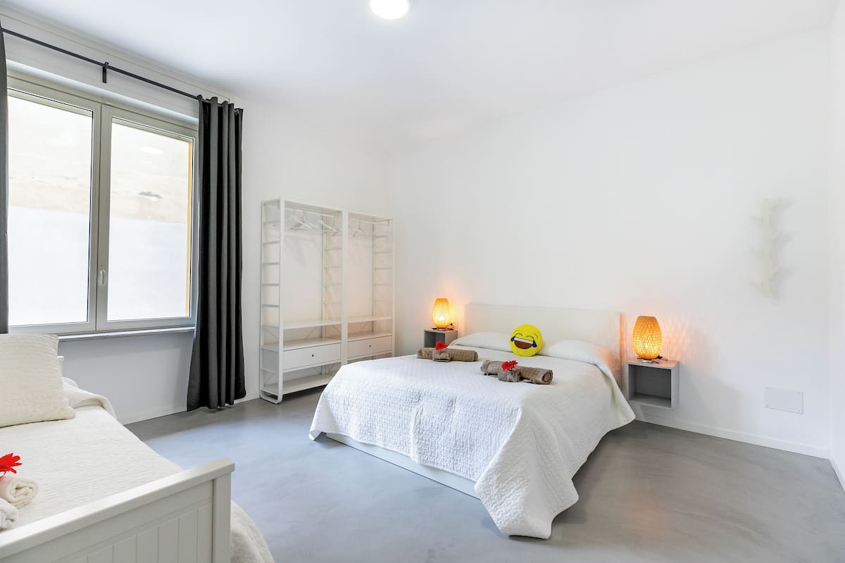 Une chambre à coucher avec un lit, des lampes de chevet, une armoire et une fenêtre avec des rideaux.