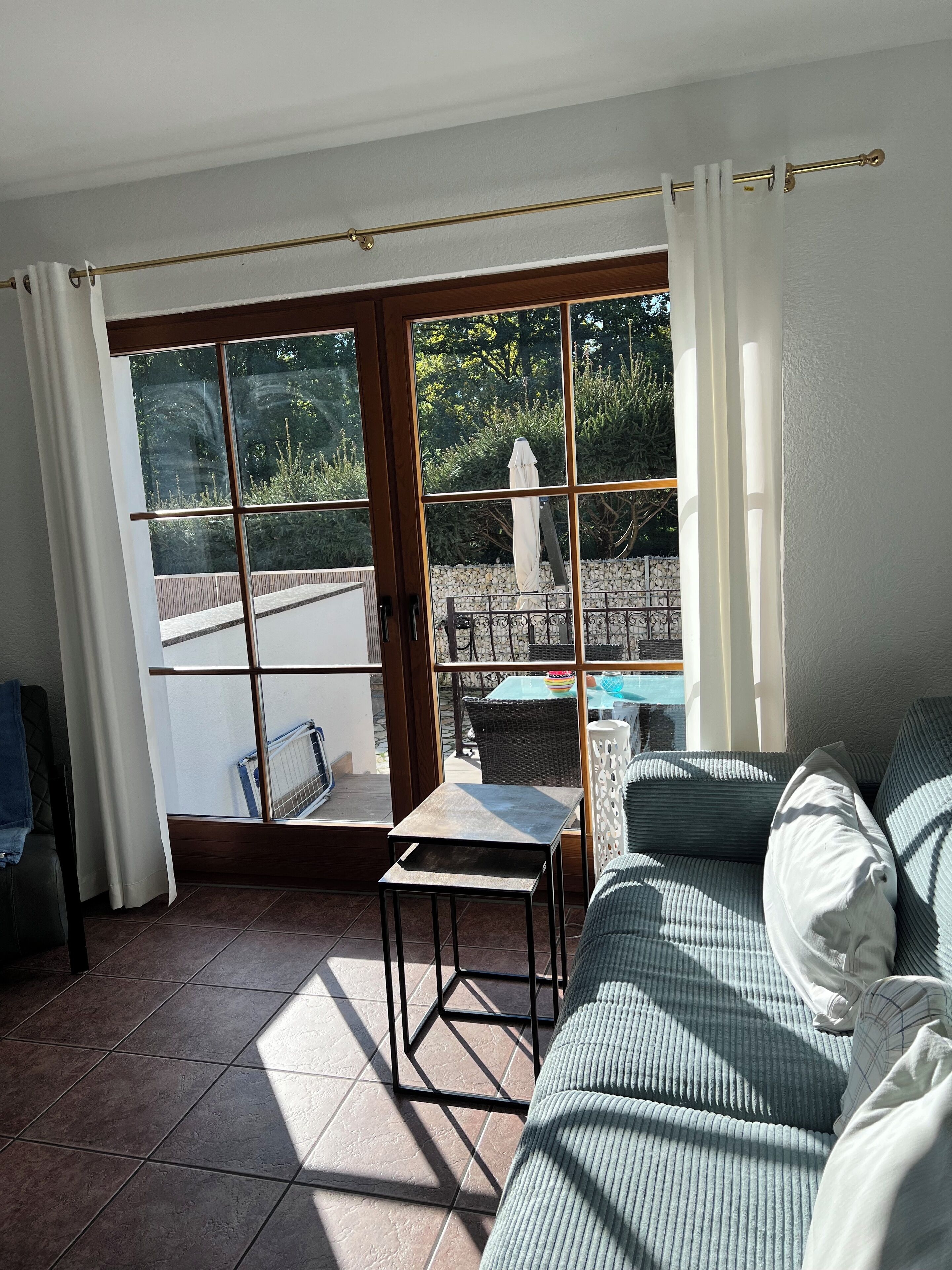 Une pièce baignée de lumière avec vue sur une piscine, une petite table et un canapé.