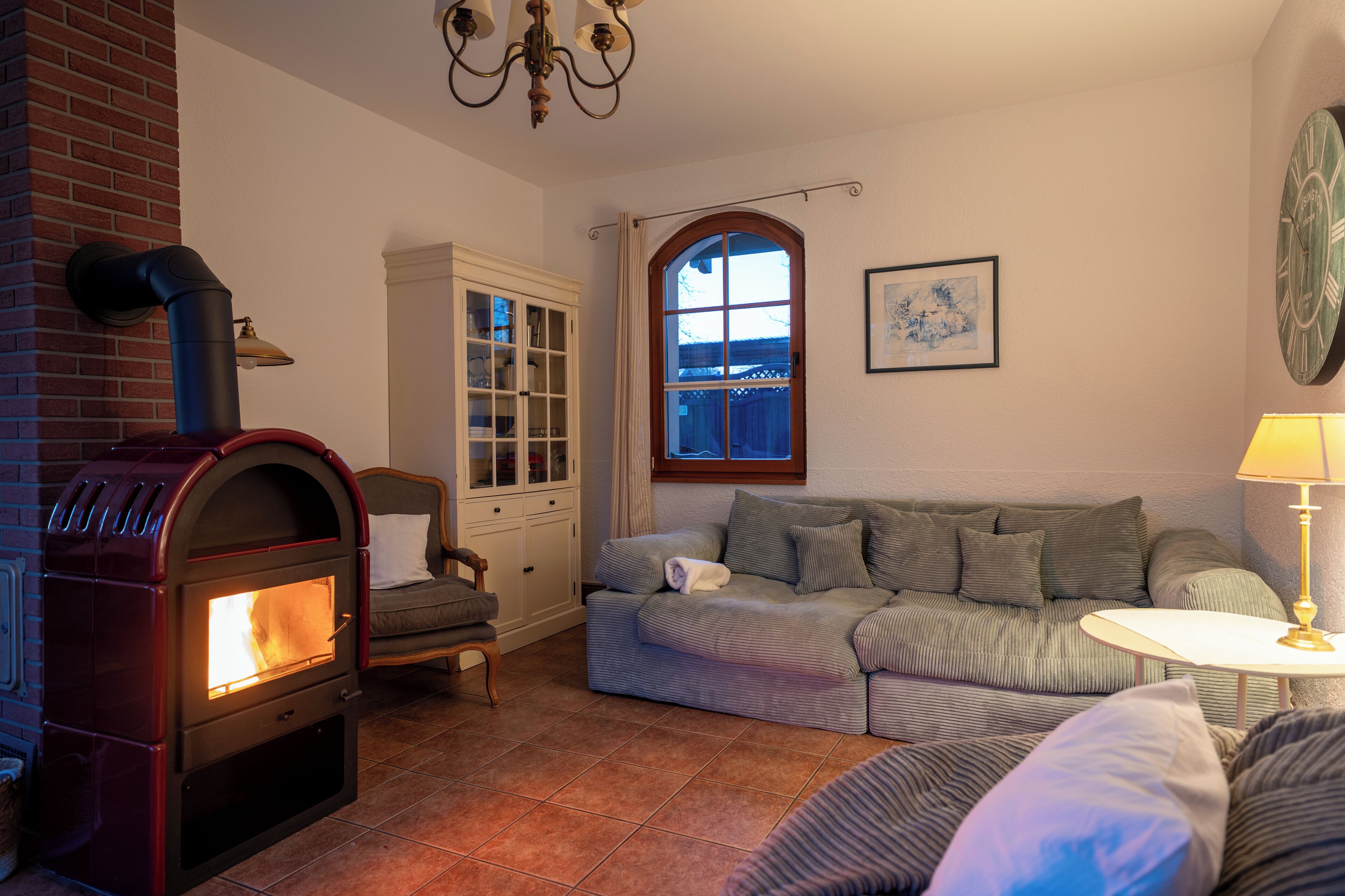 Una sala de estar acogedora con chimenea, un sofá, un armario y un ventanal.