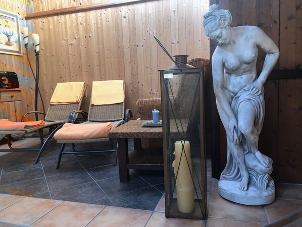 Una habitación con muebles de mimbre, una estatua y una vitrina de vidrio.