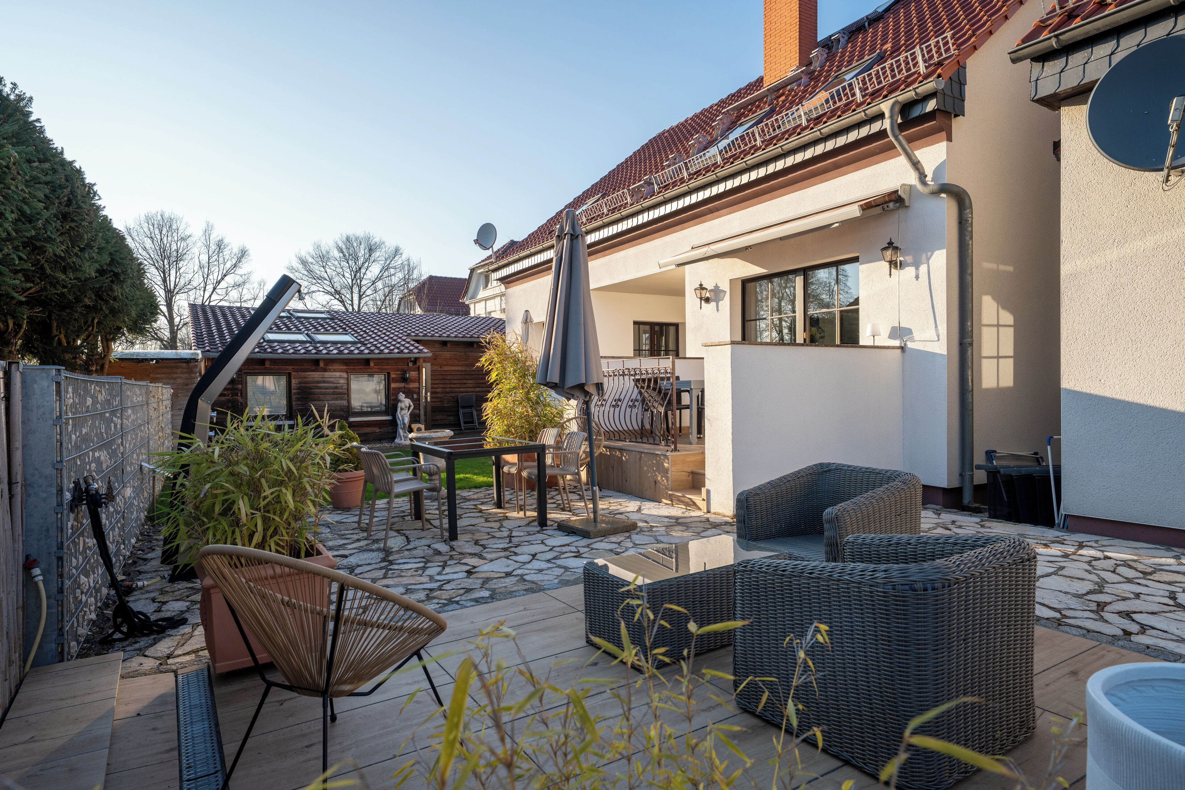 A patio area with wicker furniture, a table, and potted plants.