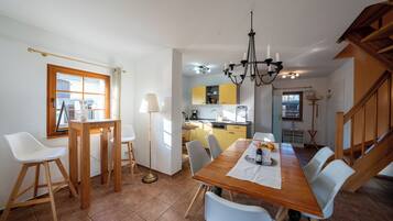 A dining area with a wooden table, white chairs, and a chandelier.