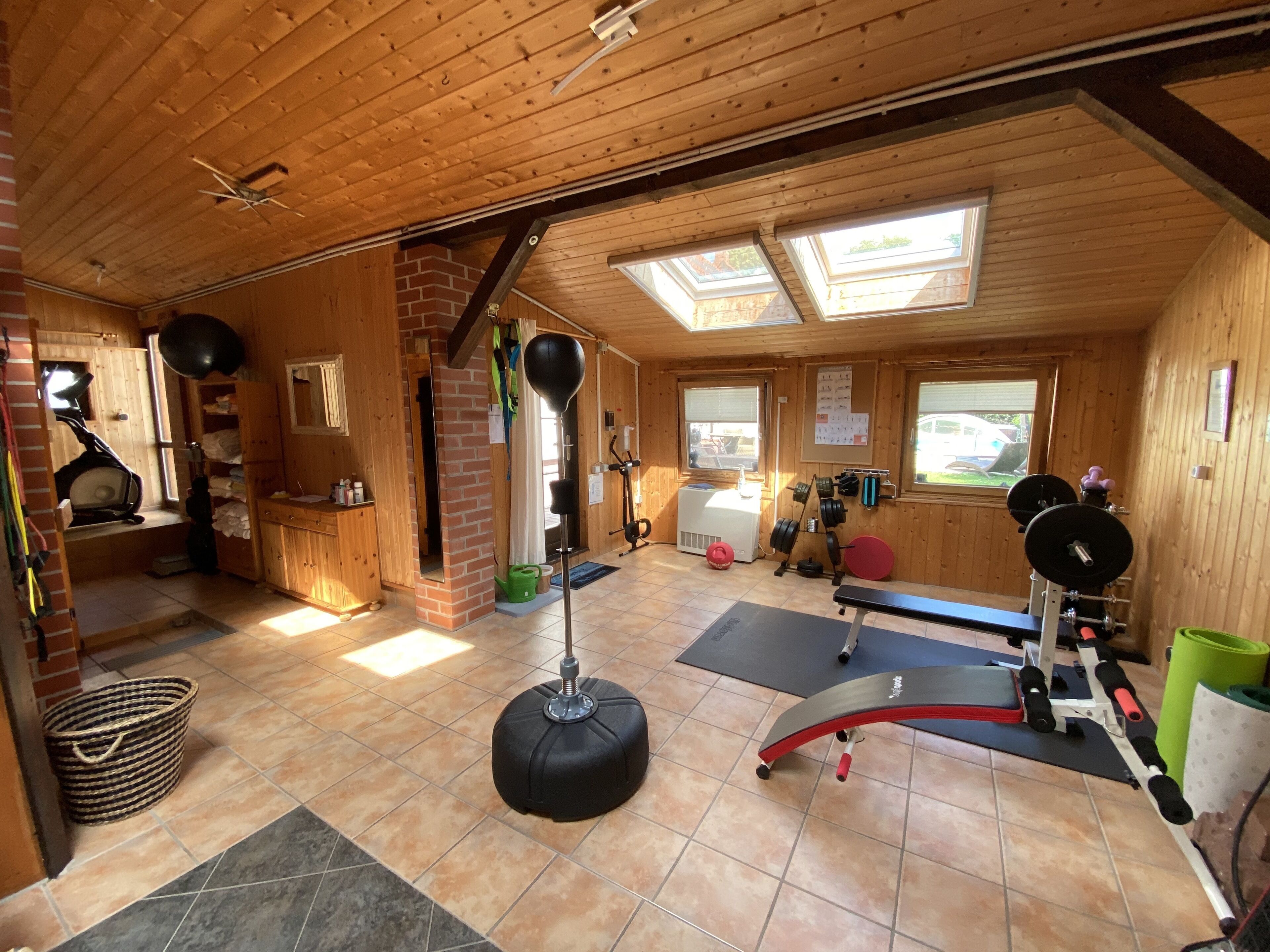 A gym with wooden walls, a ceiling fan, a mirror, a window, and exercise equipment.