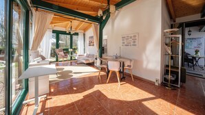 A spacious room with a wooden ceiling, a dining area, and a seating area with a sofa and chairs. - Ferienhof am Trift (Bad Saarow)