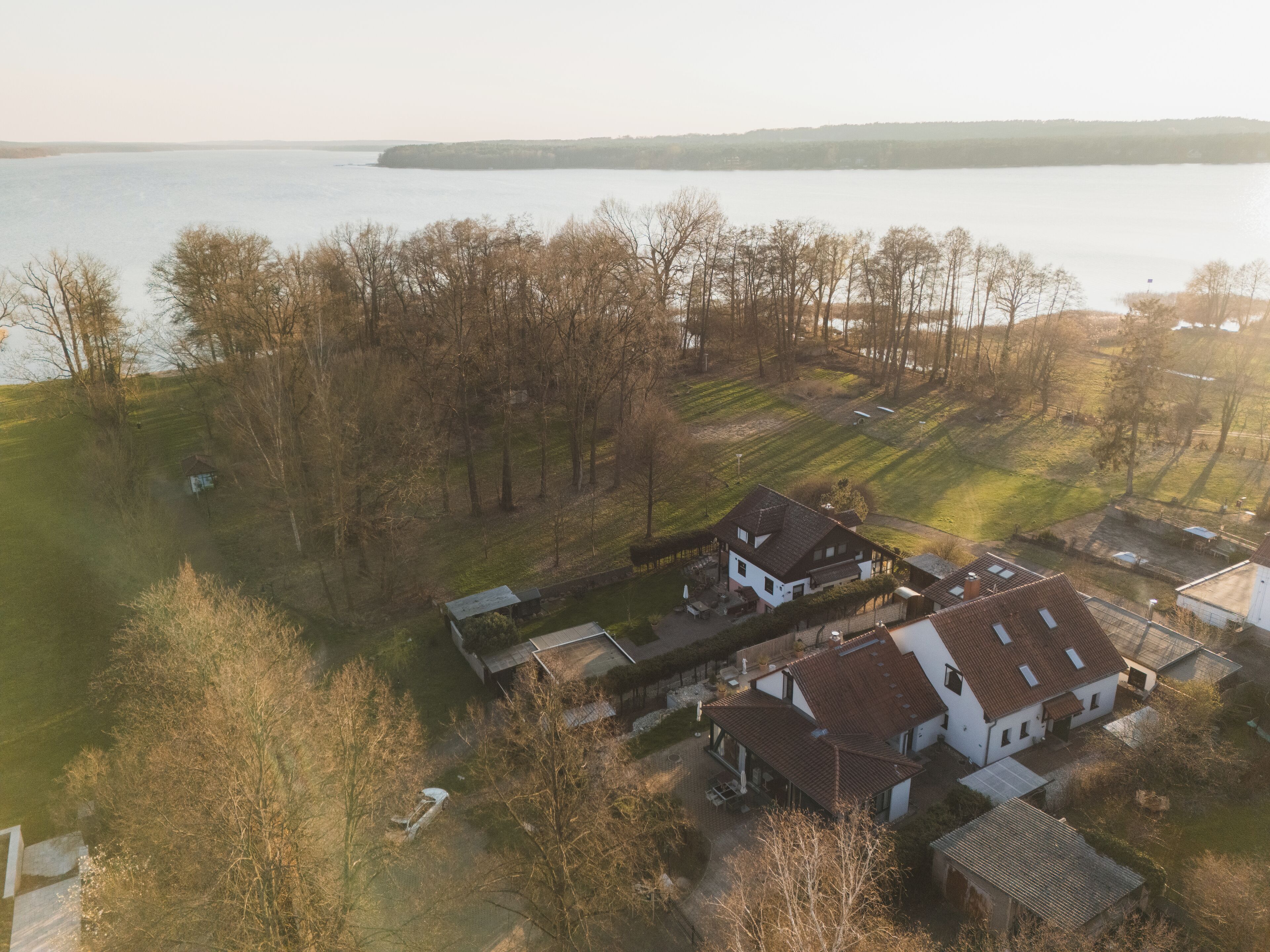 An aerial view of a residential area with houses, a lake, and a forested area.