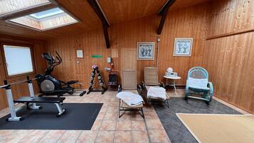 A gym with exercise equipment, a massage table, and a small table with a radio.