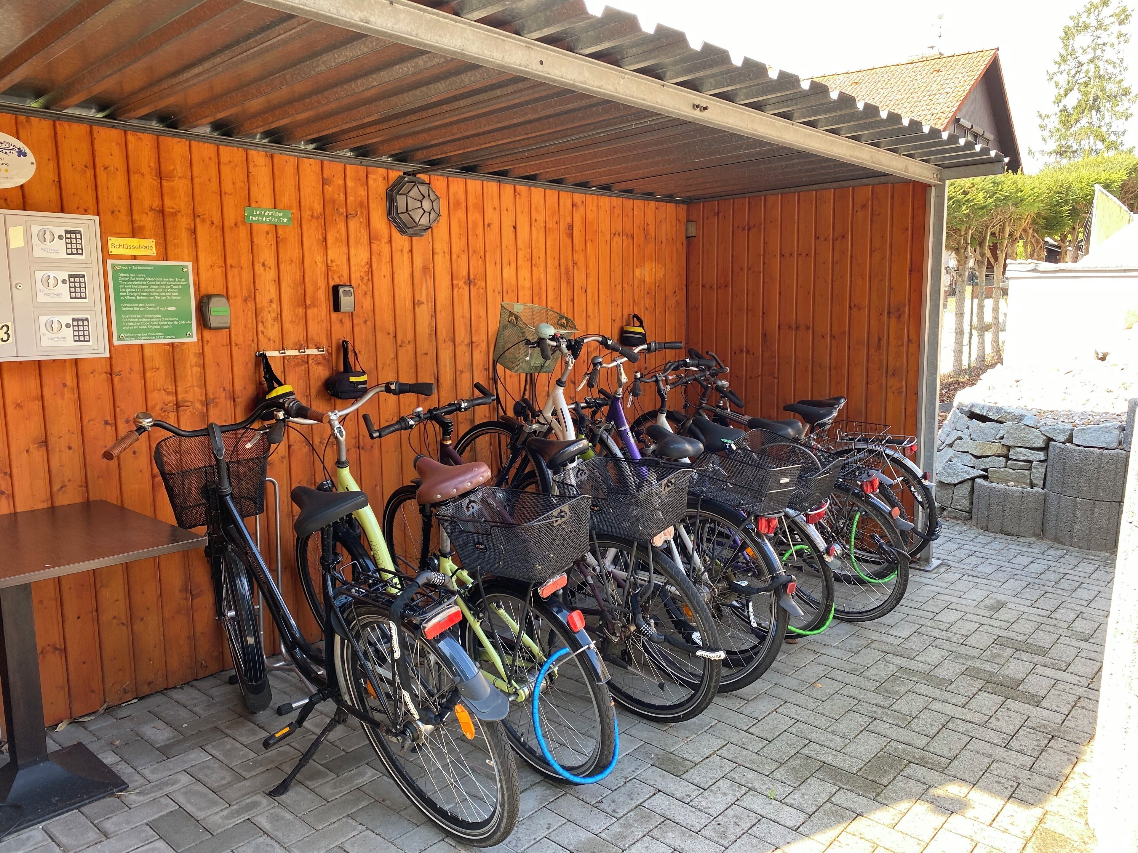 A covered bicycle parking area with wooden walls and a tiled floor.