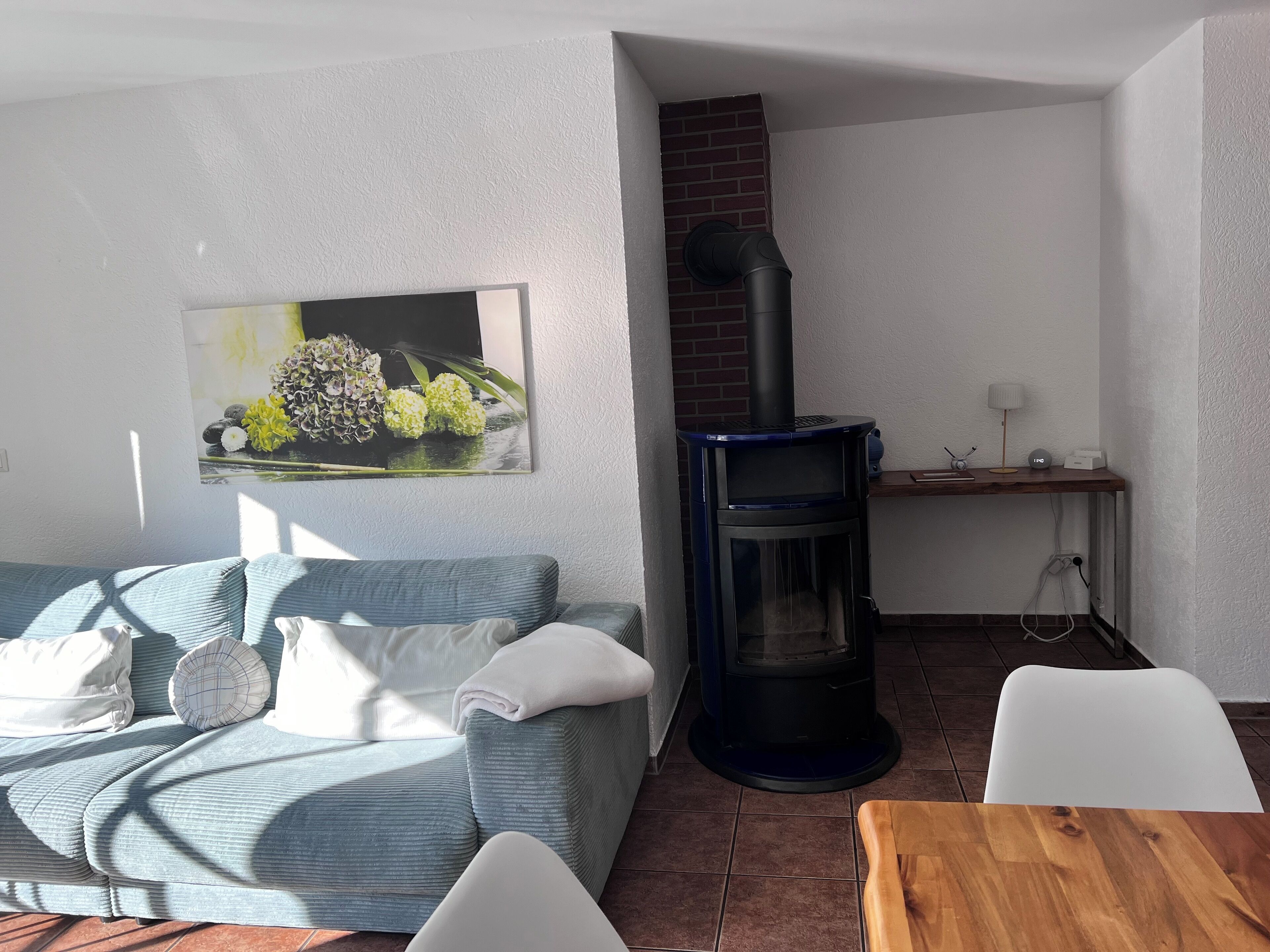 A living room with a sofa, a table, a fireplace, and a wall-mounted picture.