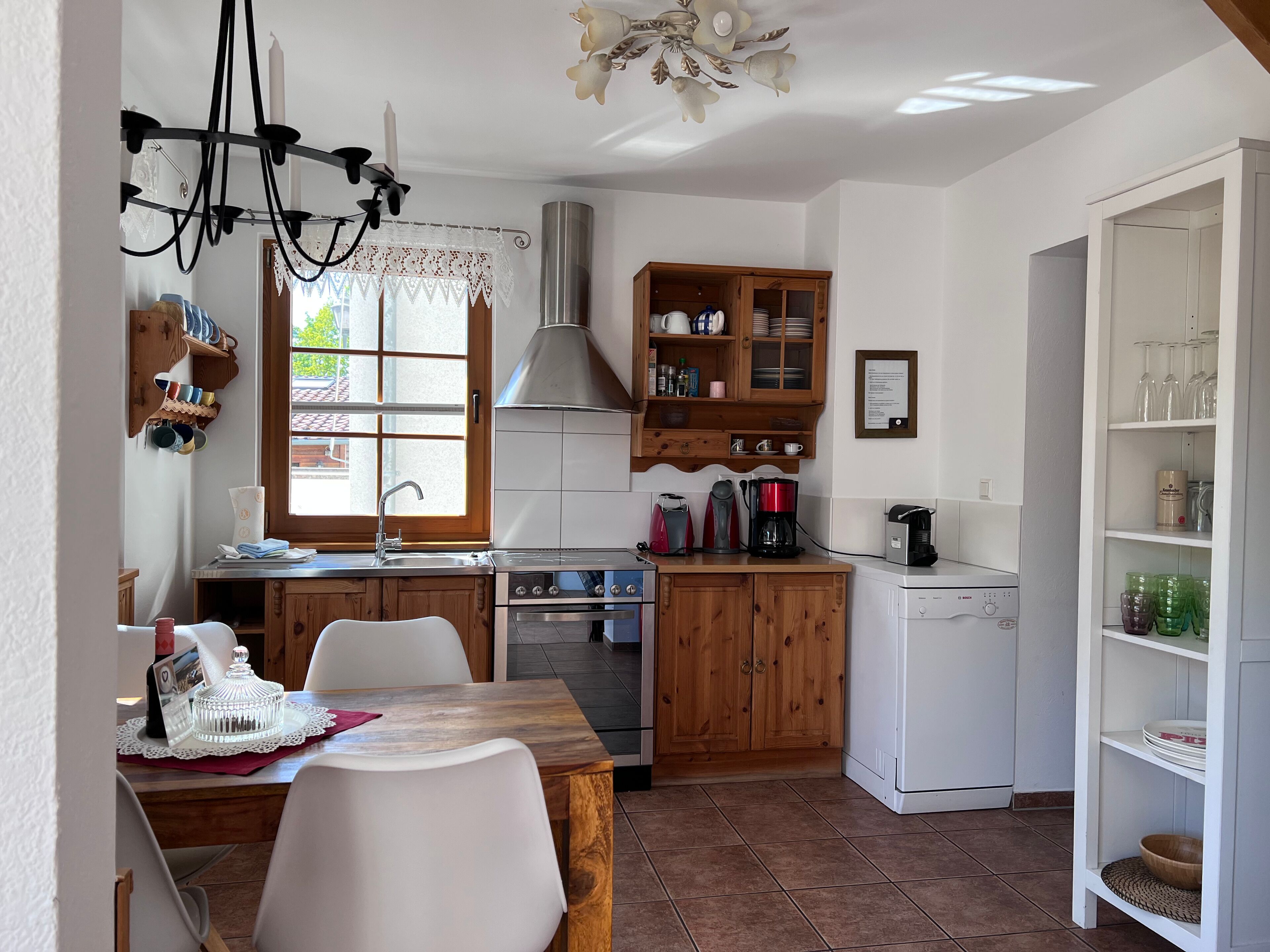 Una cucina compatta con mobili in legno, un piano cottura, una macchina da caffè e un piccolo frigorifero.