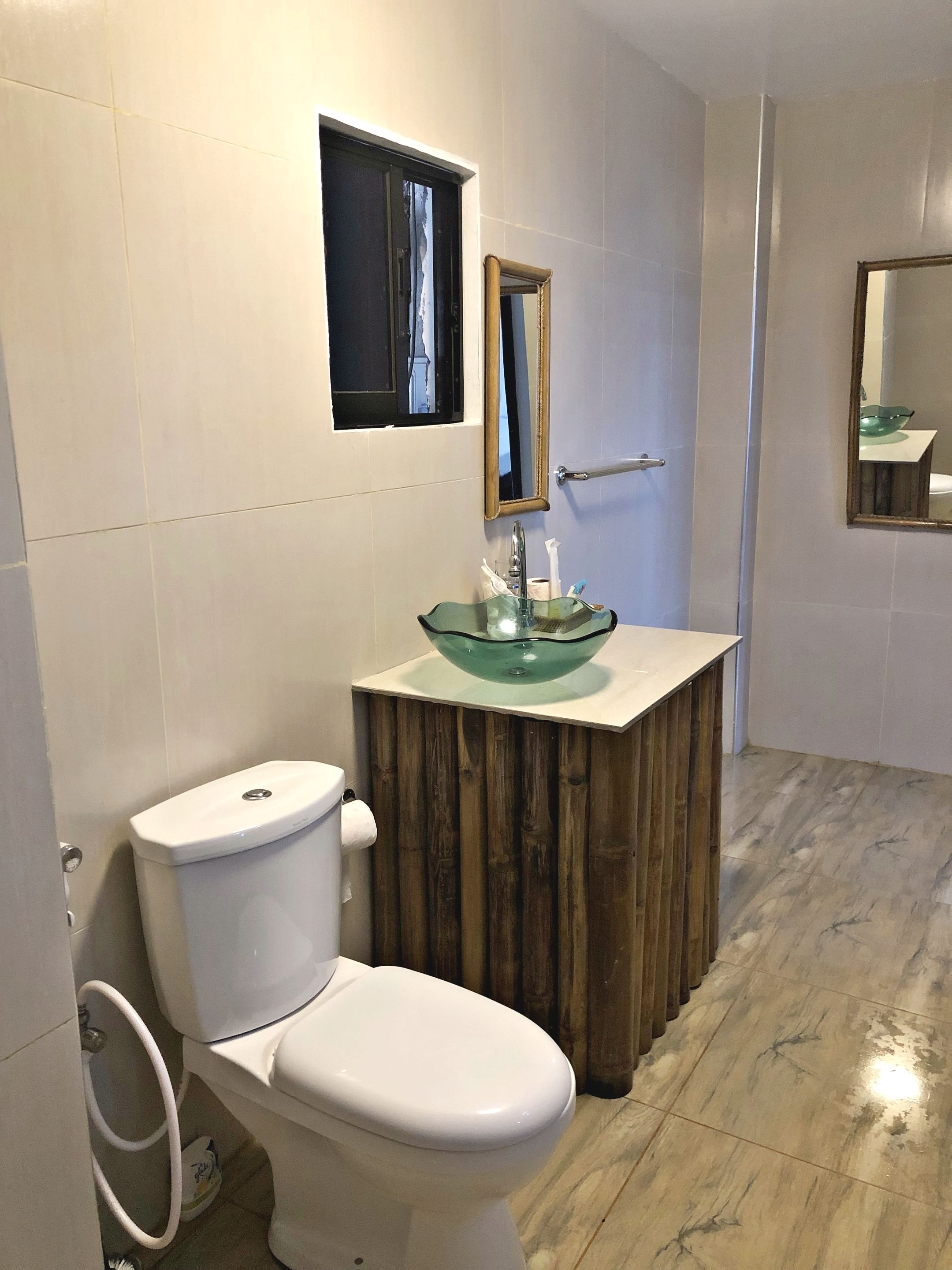 A bathroom with a white toilet, a wooden vanity with a glass sink, and a mirror above the sink.