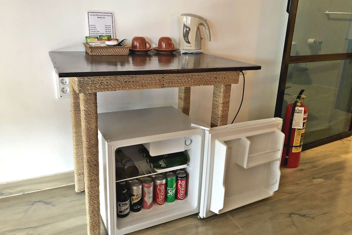 Une petite cuisine équipée d’un réfrigérateur contenant des boissons, d’une machine à café et d’un panneau affichant le menu.