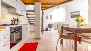 Une cuisine moderne avec des meubles blancs, un tapis rouge et un coin repas comprenant une table et des chaises.
