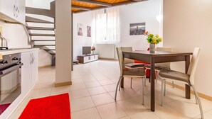 Une cuisine moderne avec des armoires blanches, un plafond en bois et un coin repas comprenant une table et des chaises.
