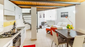 Une cuisine moderne avec des meubles blancs, une cuisinière à gaz et un coin repas comprenant une table et des chaises en bois.