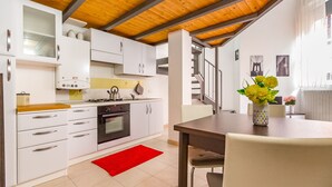 Une cuisine moderne avec des meubles blancs, un tapis rouge et un plafond en bois.