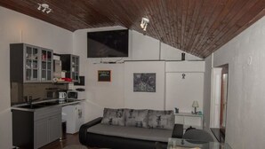 A compact living space with a kitchenette, a sofa, a dining table with fruit, and a flat-screen TV mounted on the wall. - Tequila apartments & rooms - Adults Only (Zadar)