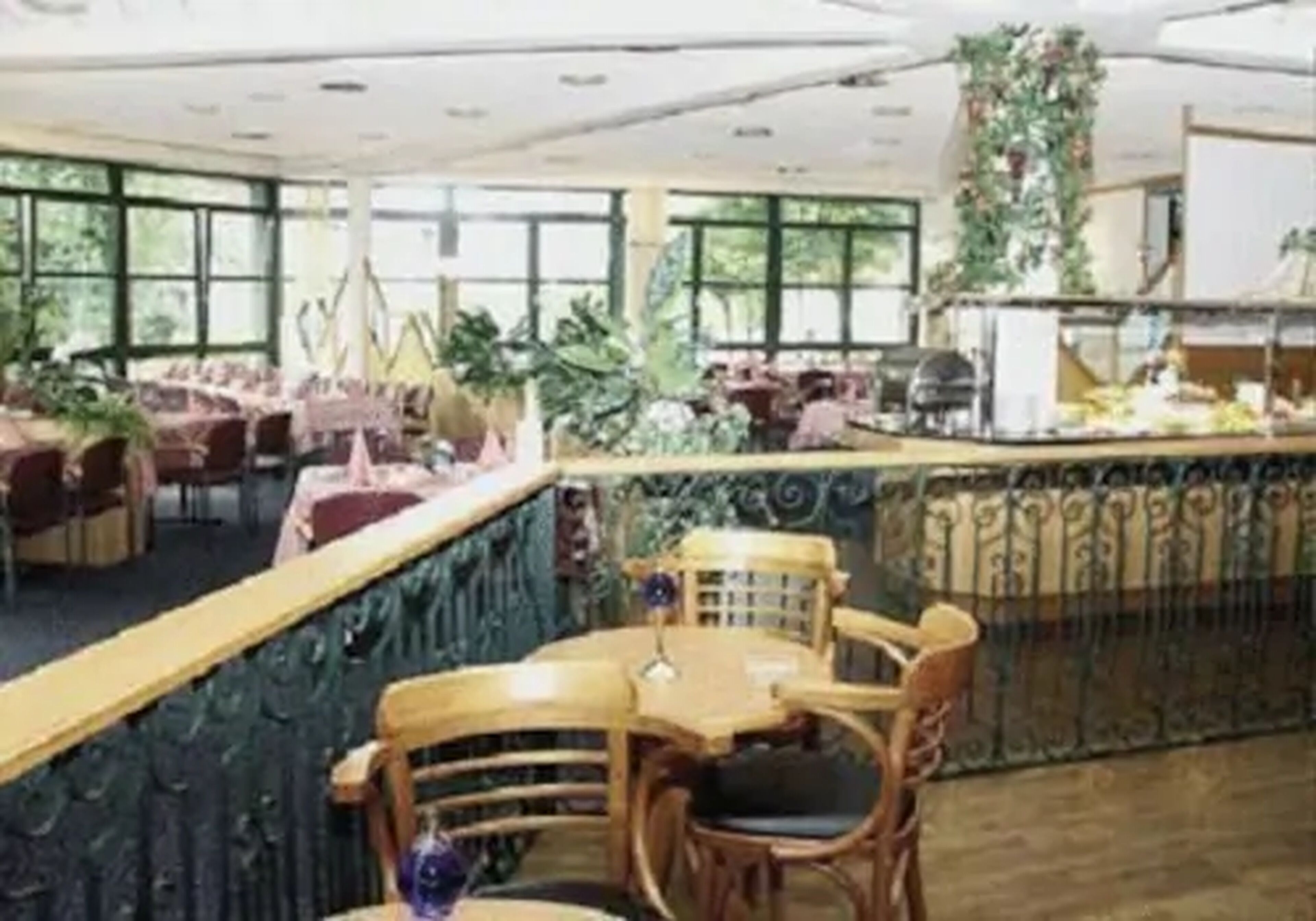 Un restaurante con techos altos, amplias ventanas y diversas opciones de asientos, incluyendo mesas y sillas.