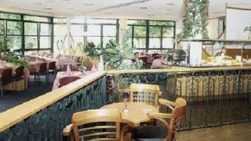 Un restaurante con techos altos, amplias ventanas y diversas opciones de asientos, incluyendo mesas y sillas.