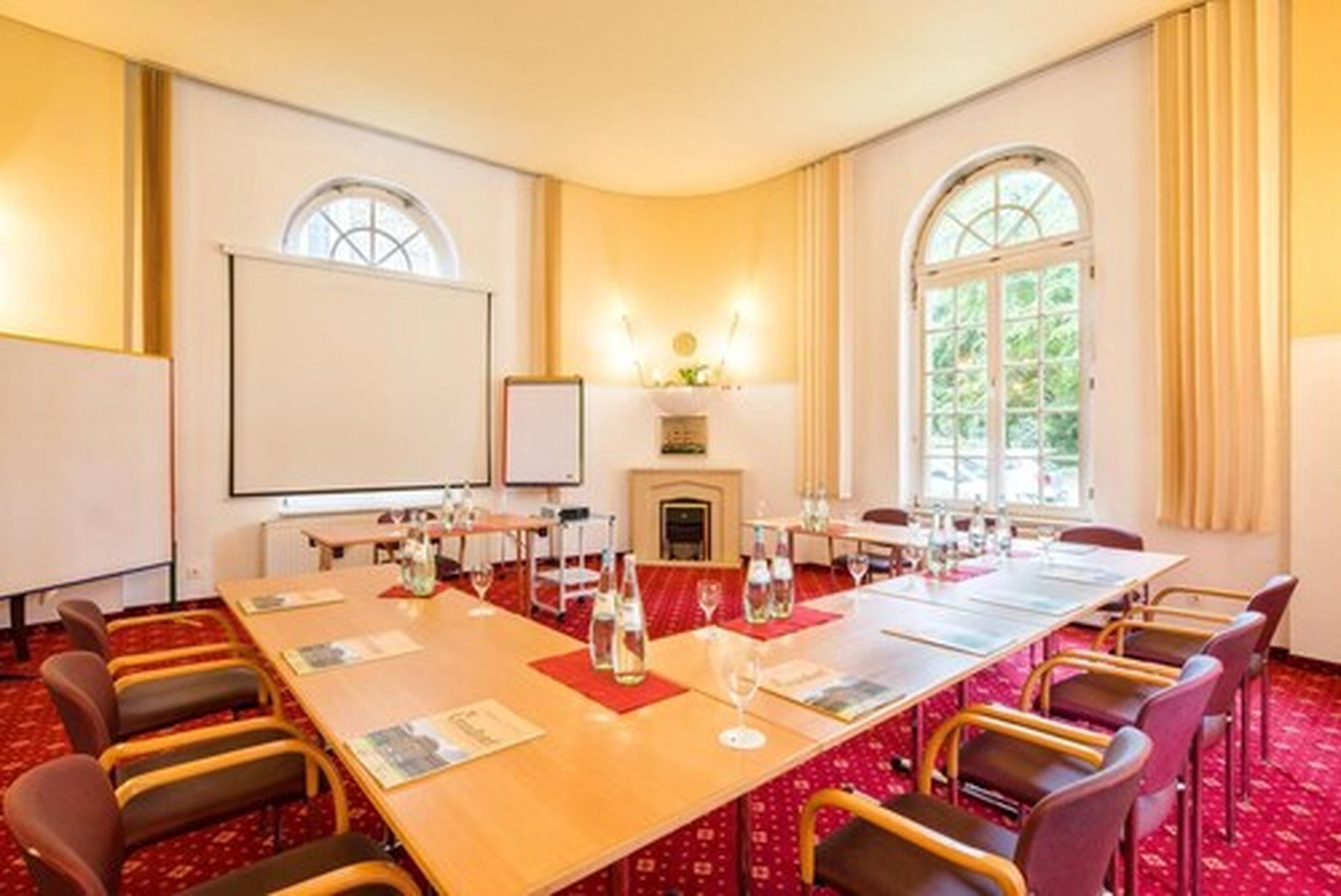 Una sala de conferencias con una mesa larga, sillas, una pantalla de proyector y una chimenea.