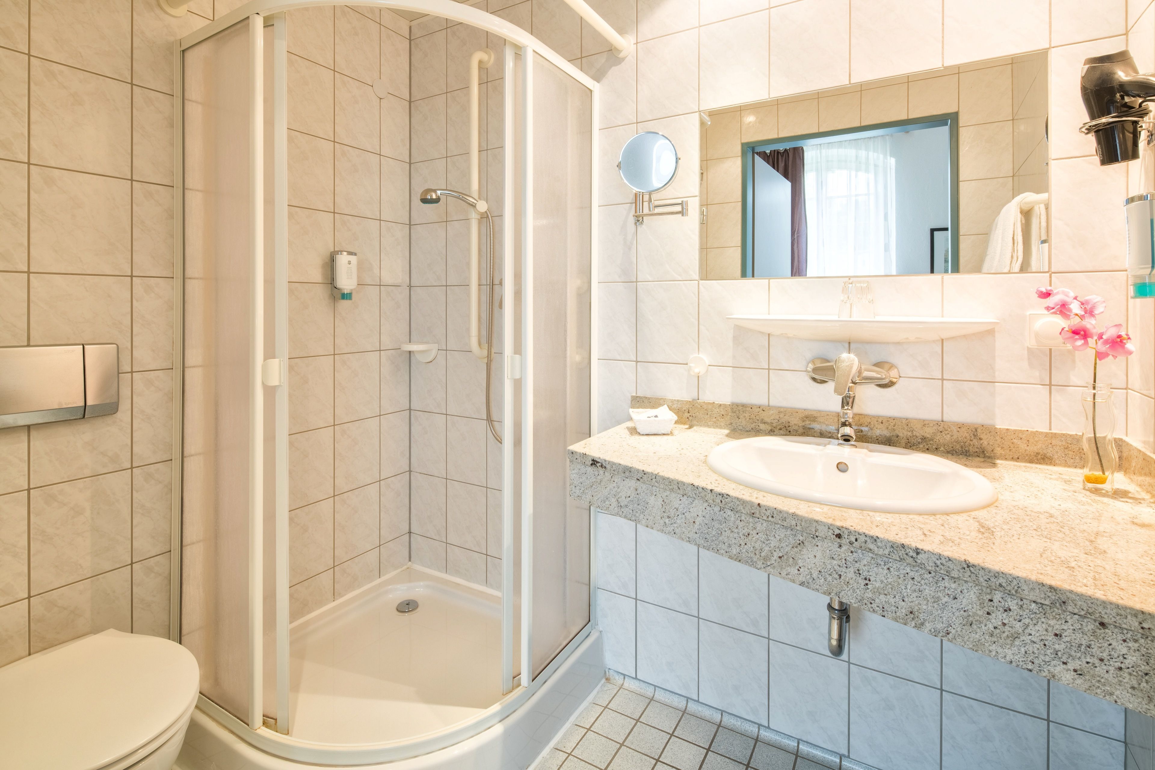 Un baño moderno con cabina de ducha de vidrio, un lavabo blanco y un espejo sobre él.