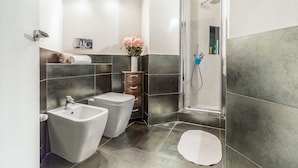 Un baño moderno con dos bidés, una ducha y un inodoro.