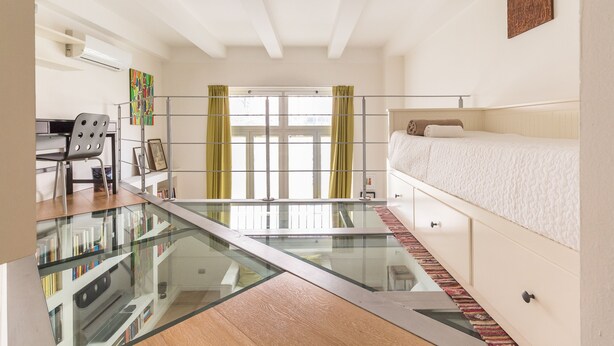 Un dormitorio moderno con piso de vidrio, una cama, un escritorio y una silla.