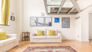 Una sala de estar con un sofá blanco, un tapete estampado y obras de arte en las paredes.