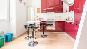 Una cocina moderna con armarios rojos, una encimera blanca y dos taburetes de bar.