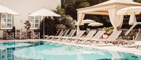 Una piscina techada, una piscina al aire libre, sombrillas