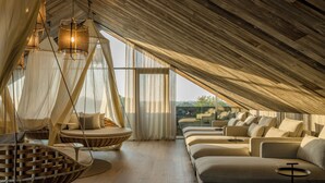 Un espacioso dormitorio tipo loft con techo alto, ventanas grandes y vistas al paisaje.