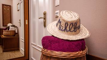 A wicker basket with a straw hat and a purple cushion in a hallway.