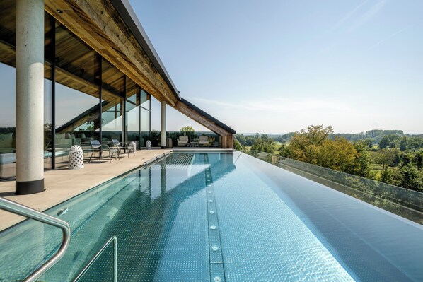 Una piscina cubierta, una piscina al aire libre, sombrillas, tumbonas