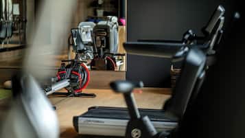 Un gimnasio en casa con equipo de ejercicio, incluyendo una caminadora, bicicleta estática y máquina elíptica.