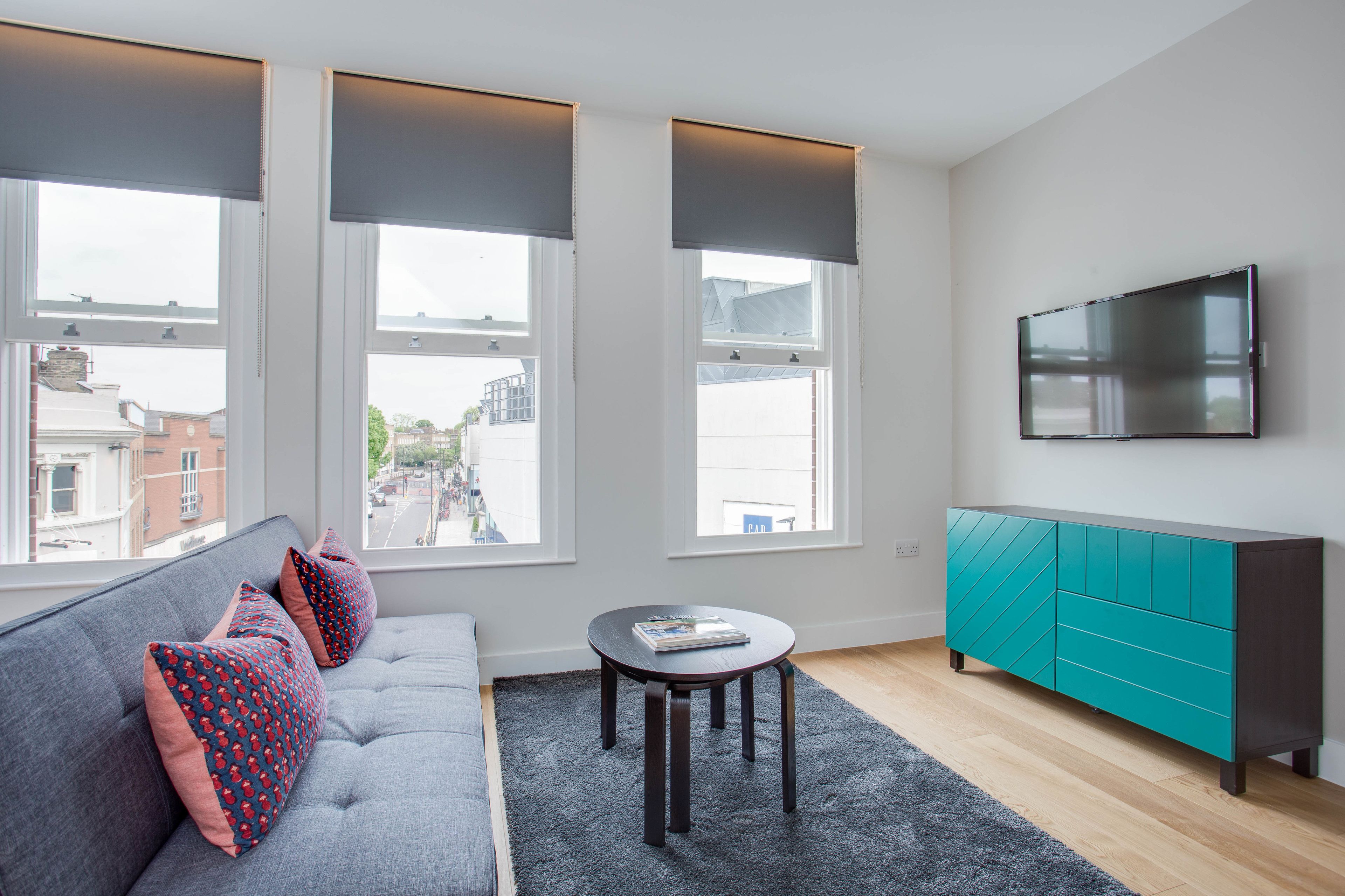 Un salon moderne avec un canapé gris, un meuble turquoise et une table ronde.