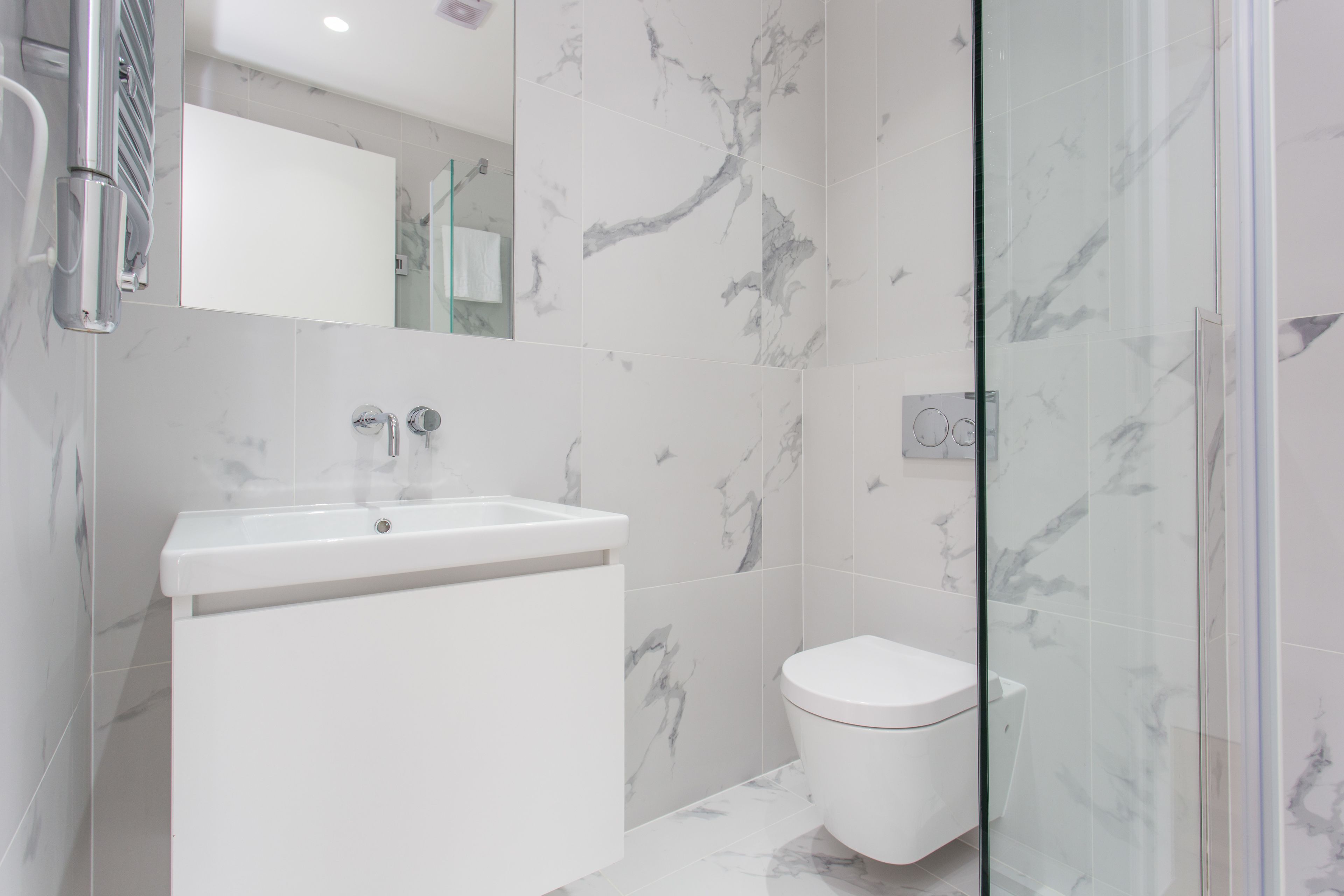 Een moderne badkamer met een witte wasbak, toilet en een douchecabine van glas.