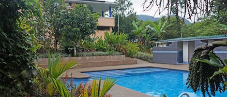 Alberca al aire libre, sombrillas en la alberca y camastros