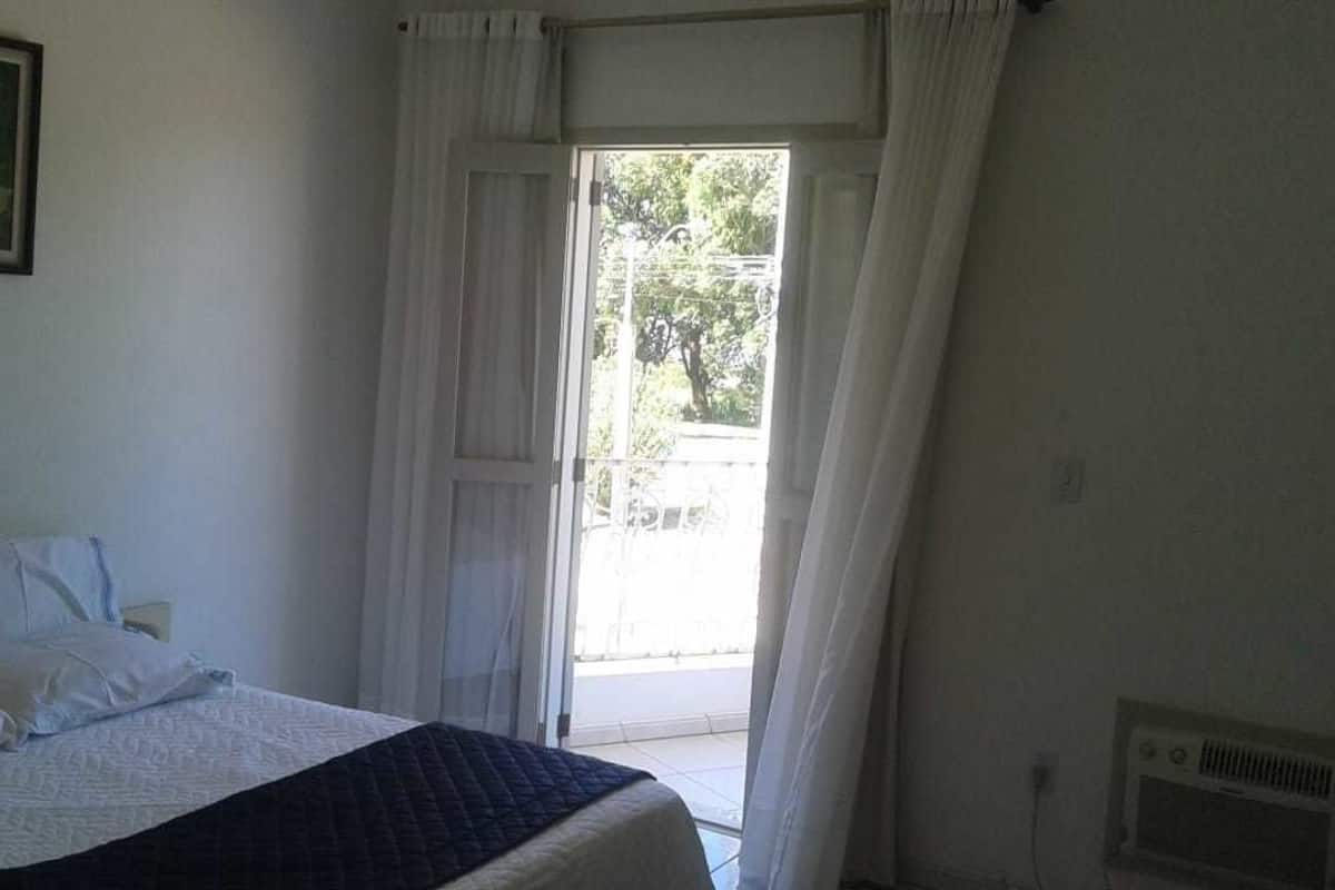 Une chambre à coucher avec un lit, une fenêtre avec des rideaux et une vue sur l’extérieur.