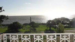 Vista costera con una valla blanca y vegetación.
