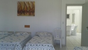 Una habitación con dos camas, una silla y un cuadro en la pared.