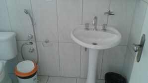 Un baño con lavamanos blanco, inodoro y ducha.