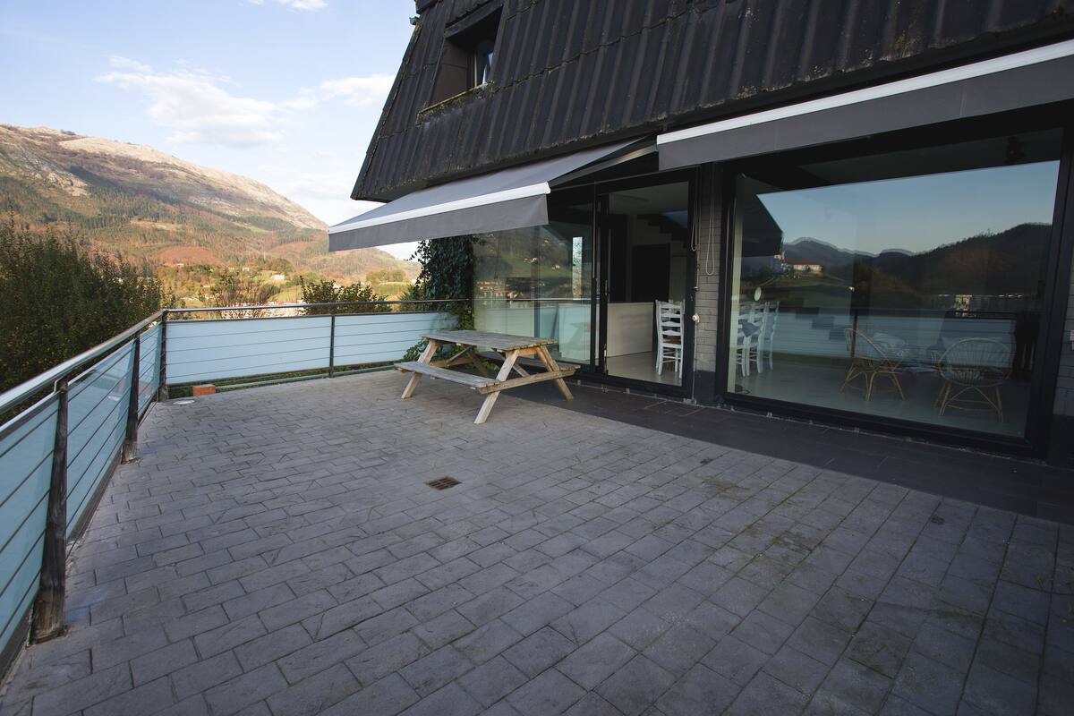 A modern building with a balcony overlooking a mountainous landscape.