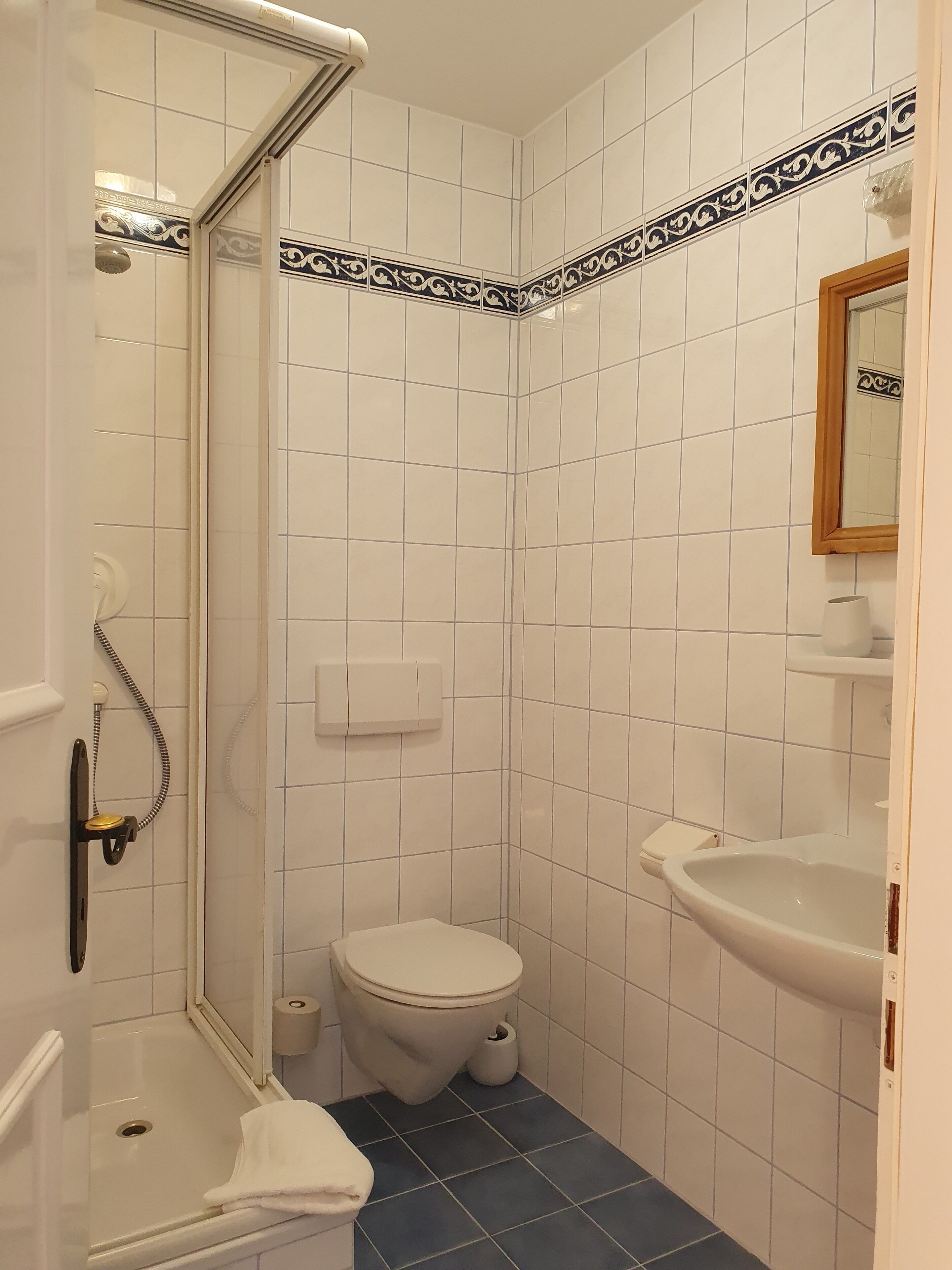 A small bathroom with a shower, toilet, and sink.