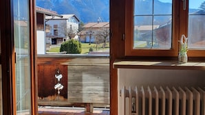 Una habitación con vistas a montañas a través de amplios ventanales, un radiador y una puerta de madera.