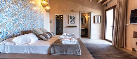 A bedroom with a large bed, patterned wall, and a wooden ceiling.